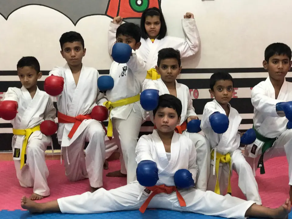 Young karate students in sparring gloves posing on the mat