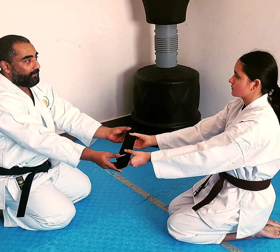 Female black belt kneeling in seiza to receive her belt from Sensei Najmal
