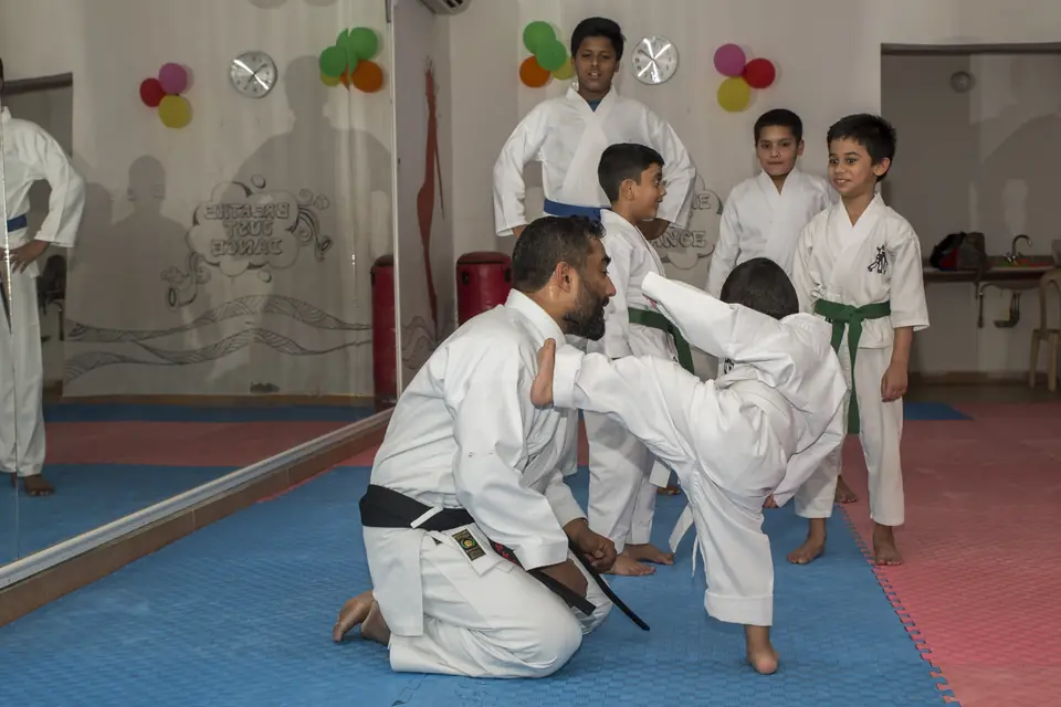 Sensei Najmal guiding a child's front kick on the mat